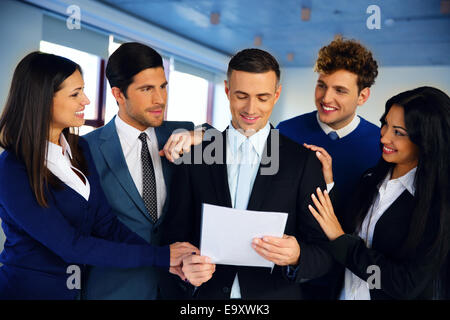 Happy colleagues congratulating businessman in office Stock Photo