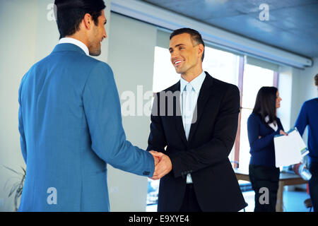 Two happy businessman handshaking in conference hall Stock Photo