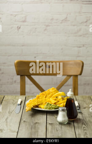 Traditional British takeaway meal of fish and chips with mushy peas on a newsprint plate Stock Photo