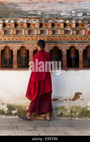 Monk standing in front of prayer wheels at Wangdue Dzong, Wangdue Phodrang, Bhutan Stock Photo