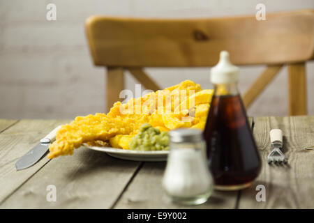 Traditional British takeaway meal of fish and chips with mushy peas on a newsprint plate Stock Photo