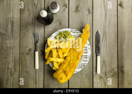Traditional British takeaway meal of fish and chips with mushy peas on a newsprint plate Stock Photo