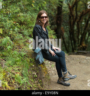Woman resting on a rock at Tango Monastery, Thimphu, Bhutan Stock Photo