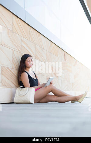 A young woman relaxing whilst looking at content on a tablet device Stock Photo