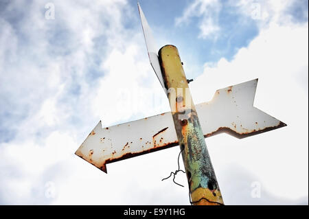 Rusty arrow signpost on a rusty pole Stock Photo