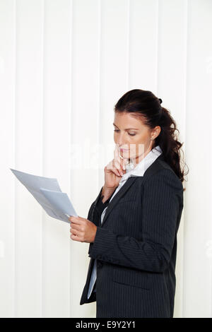 Businesswoman reading a letter in the office. Message from the lawyer or tax office. Stock Photo