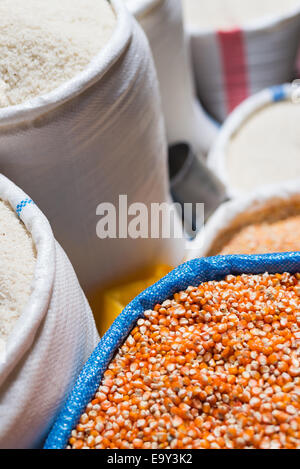 Bag of  yellow - orange corn for sell in south east asian market with sacks of white rise in the background. Selective focus. Stock Photo