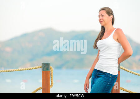 beautiful girl on the pier looks attentively aside Stock Photo