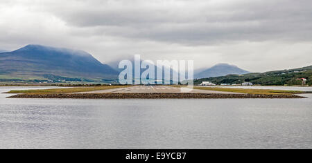 View from the end of runway at Akureyri airport in Iceland. A small plane is taking off. Stock Photo