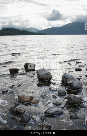 A landscape image of the shore of Loch Lomond in the scottish Highlands Scotland UK  showing rocks in the foreground. Stock Photo