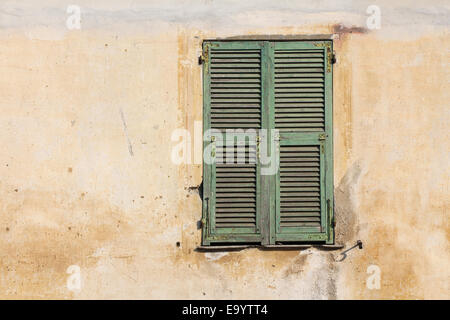 Old green wooden window on the old cracked facade Stock Photo