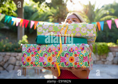 Girl carrying pile of birthday presents Stock Photo
