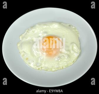 Fried (sunnyside) egg on a white plate against a black background. Stock Photo