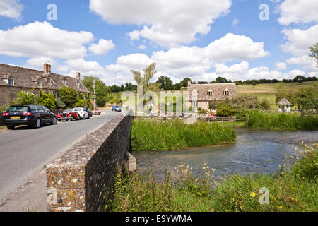 The Swan Inn on the banks of the River Windrush in the Cotswold village of Swinbrook, Oxfordshire UK Stock Photo