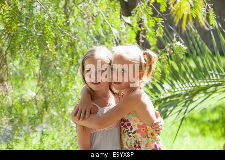 Candid portrait of two girls with arms around each other in garden Stock Photo