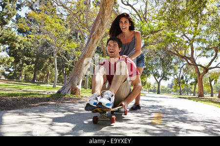 Young couple skateboarding in park Stock Photo