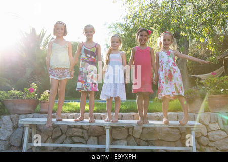 Portrait of five girls standing on garden bench Stock Photo