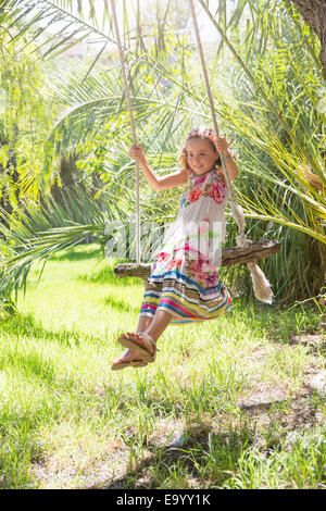 Girl sitting swinging on tree swing in garden Stock Photo