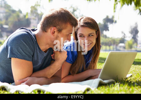 Couple using laptop in park Stock Photo