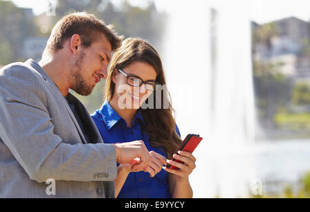 Businessman and woman using smartphone Stock Photo