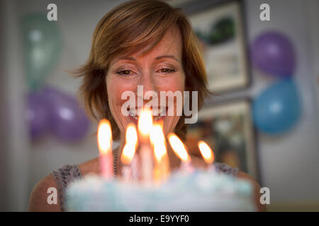 Mature woman holding birthday cake with candles Stock Photo