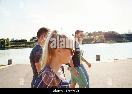 Four young friends walking along riverside Stock Photo