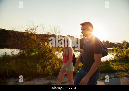 Young couple strolling along riverside at sunset Stock Photo