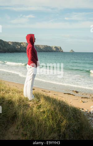 Mature woman standing gazing at sea view, Camaret-sur-mer, Brittany, France Stock Photo