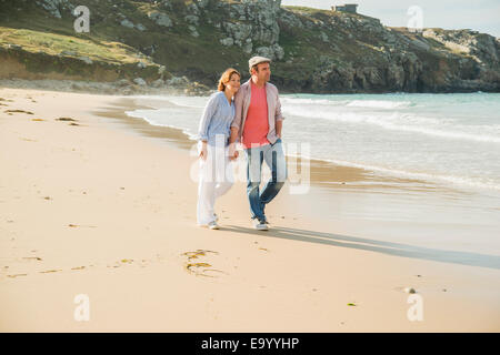 Mature couple holding hands strolling on beach, Camaret-sur-mer, Brittany, France Stock Photo