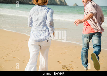 Mature couple running on beach, Camaret-sur-mer, Brittany, France Stock Photo