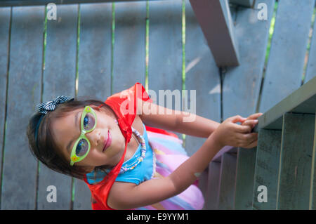 Young girl wearing cape, climbing wooden steps, high angle view Stock Photo