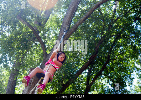 Young girl sitting on rope tree swing Stock Photo