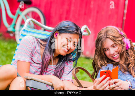 Two teenagers wearing headphones, listening to music, outdoors Stock Photo