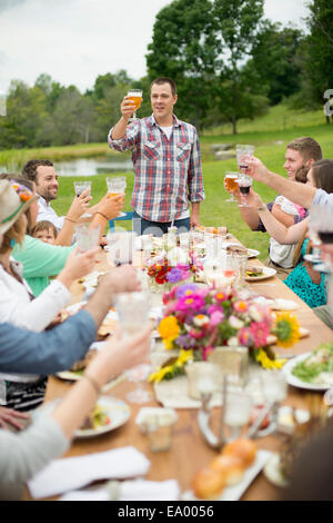 Family and friends making a toast at outdoor meal Stock Photo