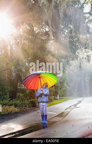 Boy carrying umbrella and looking up on street Stock Photo