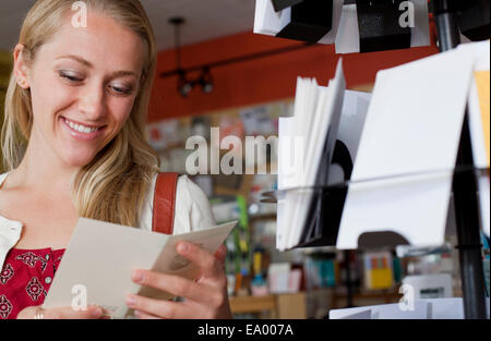 Female customer looking at greetings card in stationery shop Stock Photo
