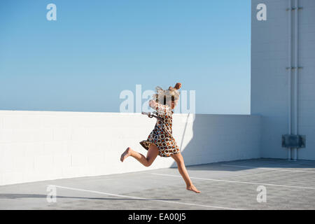 Girl jumping barefoot on building rooftop Stock Photo