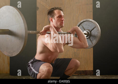 Mid adult male weightlifter lifting barbell in gym Stock Photo