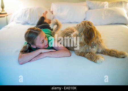 Young girl lying on bed next to dog Stock Photo