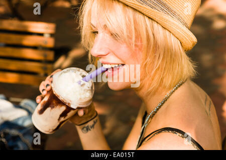 Young woman drinking frappe with a straw in park Stock Photo