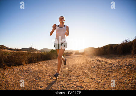 Young woman jogging on sunlit path, Poway, CA, USA Stock Photo