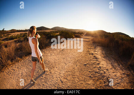 Young female jogger on path, drinking, Poway, CA, USA Stock Photo