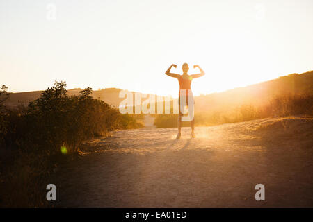 Female jogger flexing arms in sunlight, Poway, CA, USA Stock Photo