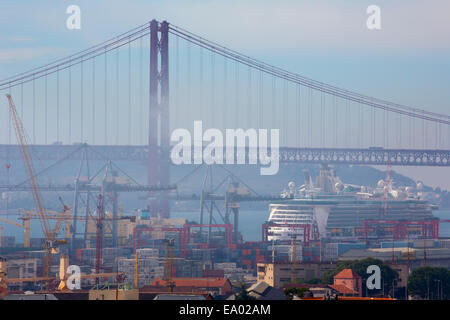 Lisbon, Portugal.  Misty morning.  Dock area and 25th of April bridge. Ponte 25 de Abril.  Luxury liner in dock. Stock Photo
