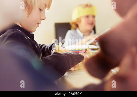 Young boy opening up Christmas present at table Stock Photo