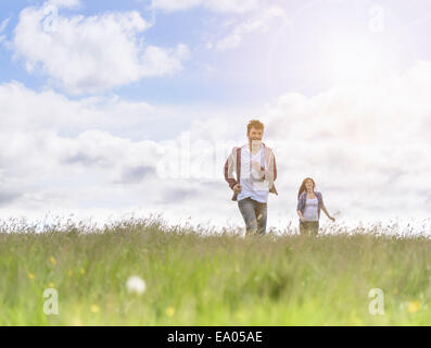 Young couple running through meadow under bright sunshine Stock Photo