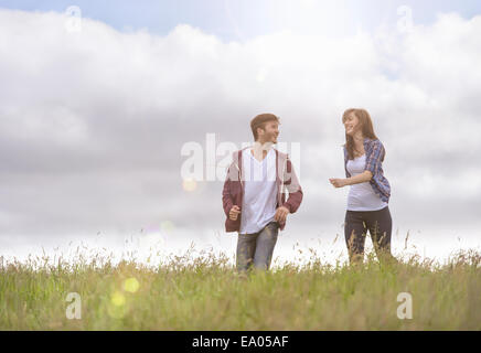 Young couple running through meadow under bright sunshine Stock Photo