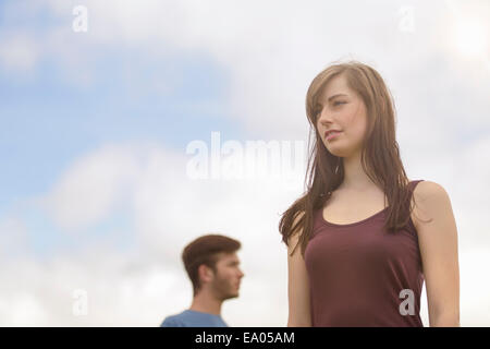 Young couple standing apart and looking away under bright blue sky