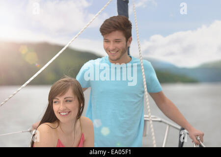 Young couple on bow of yacht sailing on lake under bright sunlight Stock Photo