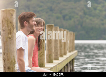 Young couple laughing together on jetty over lake Stock Photo